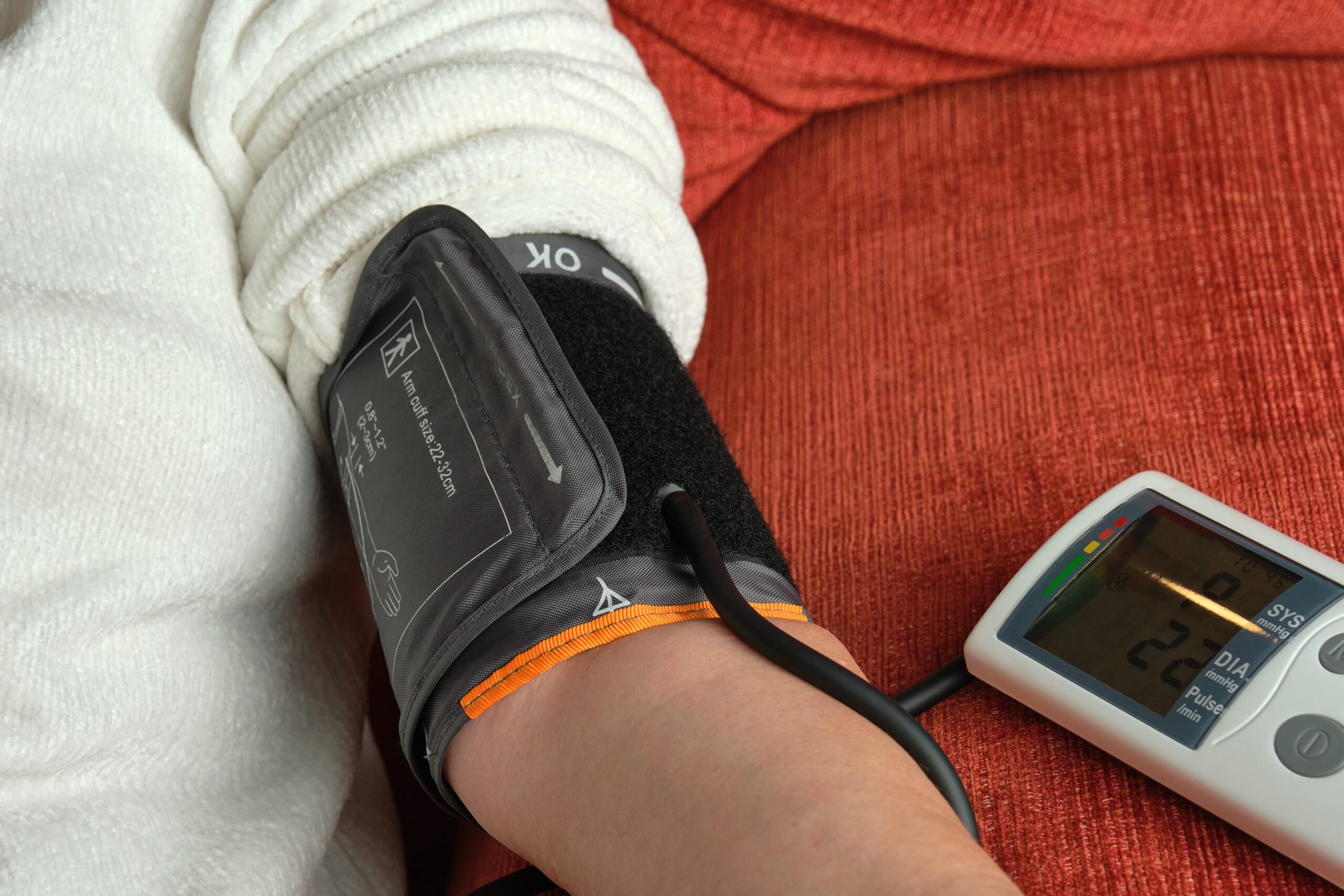 unrecognizable older woman taking her blood pressure with a digital blood pressure monitor
